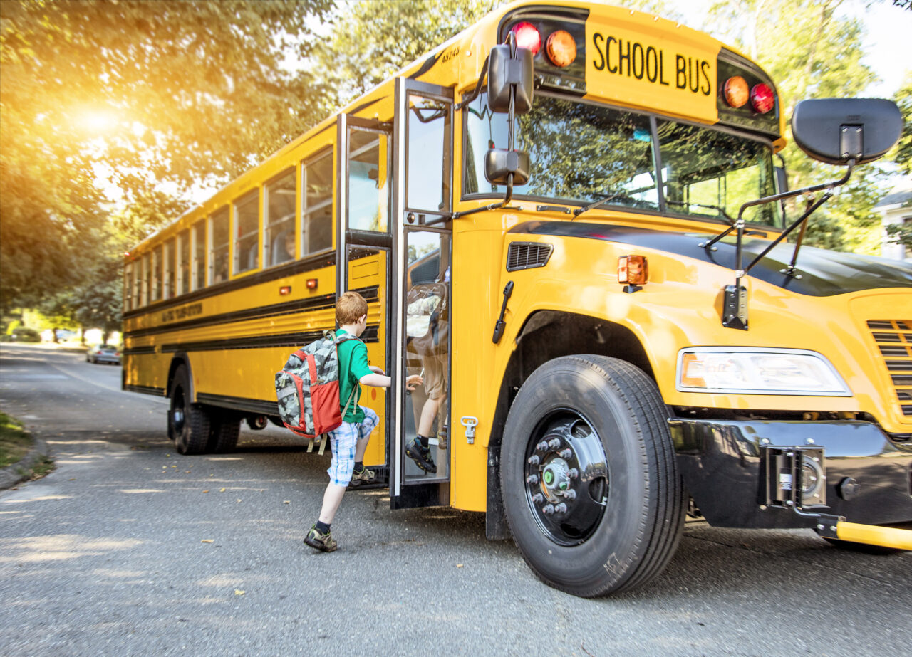 Child enters school bus at bus stop.