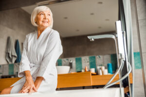 Older woman getting ready in bathroom using talcum powder