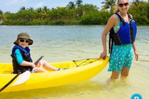 Mother pulls young child in kayak during summer excursion.