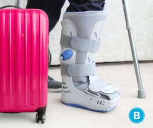 Person's broken leg in cast with crutch and suitcase