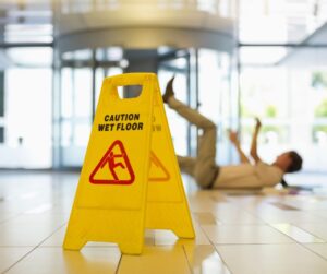 Man slips and falls on wet floor with warning sign present.