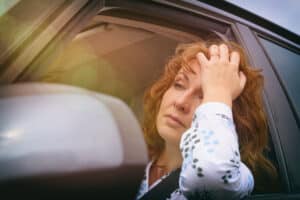 Woman stressed looking out car window waiting in traffic