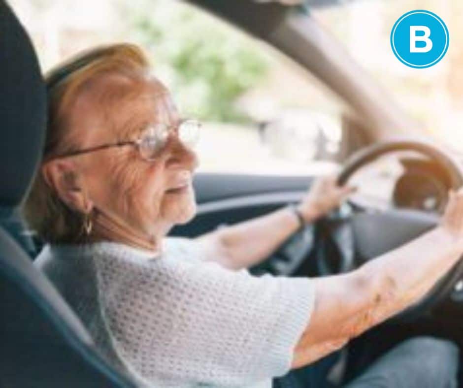 Older female driver behind wheel of car.