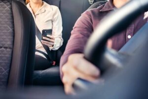 Passenger in rideshare using phone in backseat