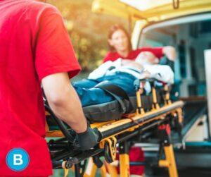 emergency medical responders load injured patient into back of ambulance on stretcher