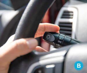 hand on steering wheel prepares to push turn signal lever