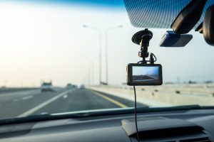 Dashboard camera fastened to interior of front windshield with highway shown in distance