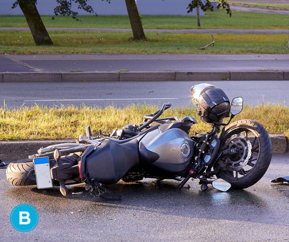 Motorcycle damaged laying in road after accident with helmet on top