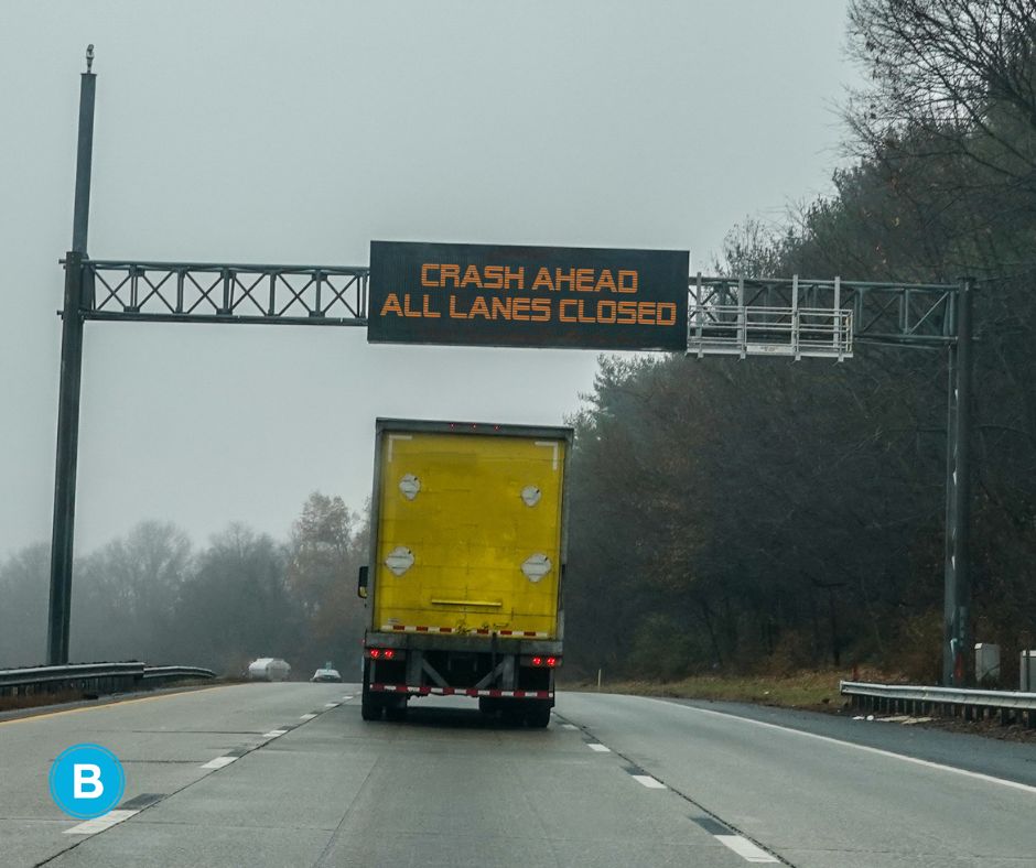 accident alert sign on highway above yellow box truck