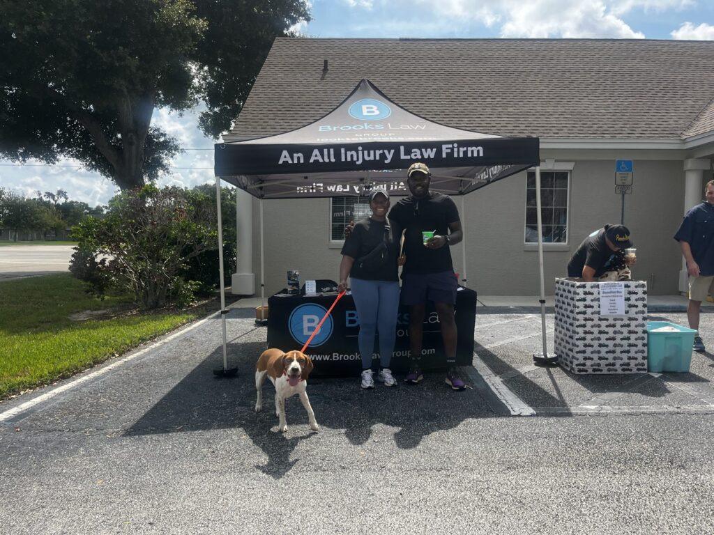 Two people with a beagle on a leash at the Brooks Law Group tent during the pet adoption event in Winter Haven